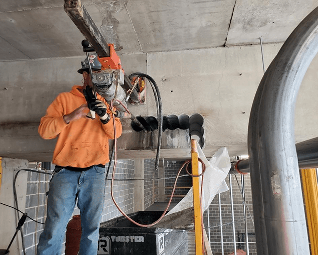Worker drilling into concrete ceiling.