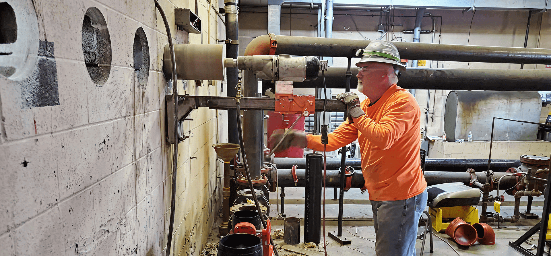 Worker drilling holes in a concrete wall.