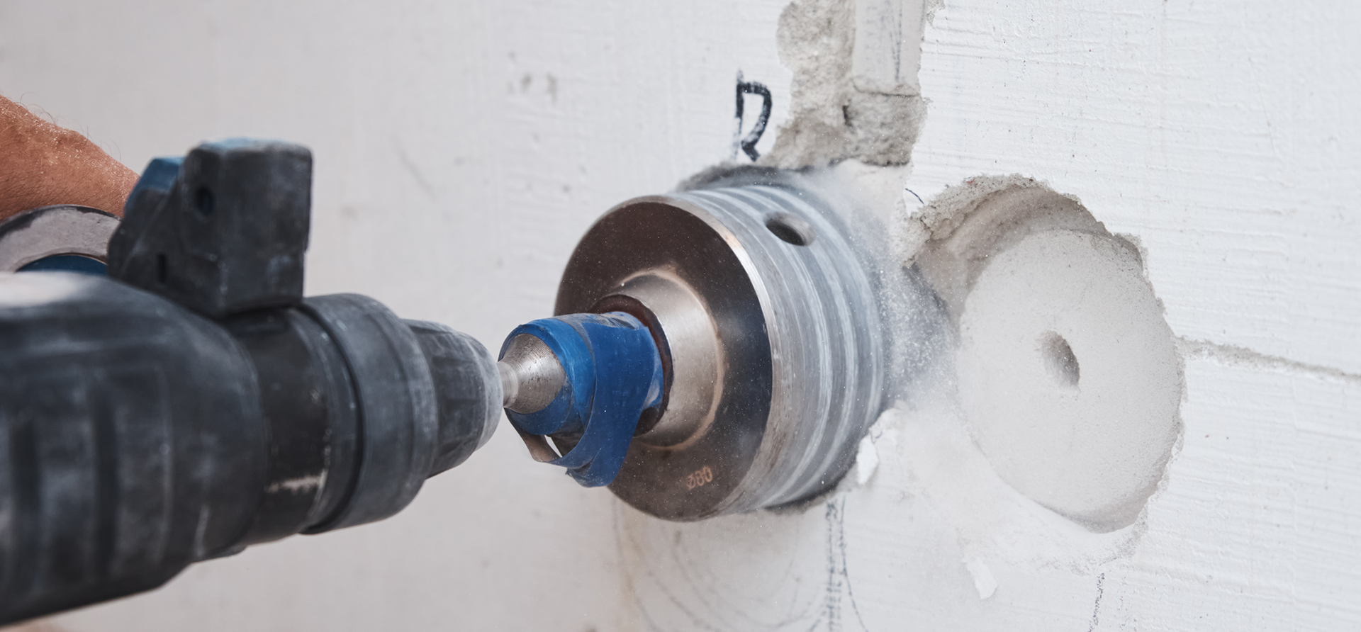 Drilling a hole in a white wall.